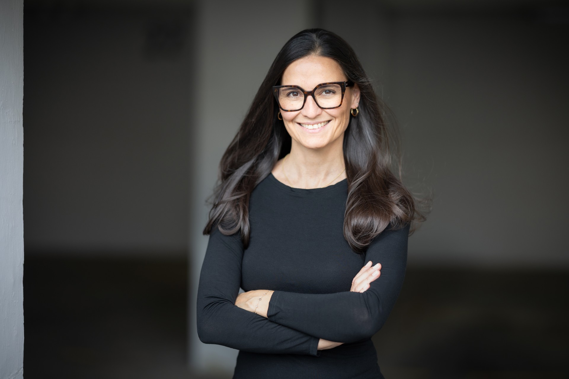 Isabel Espinosa mit verschränkten Armen, Porträt in dunkler Umgebung